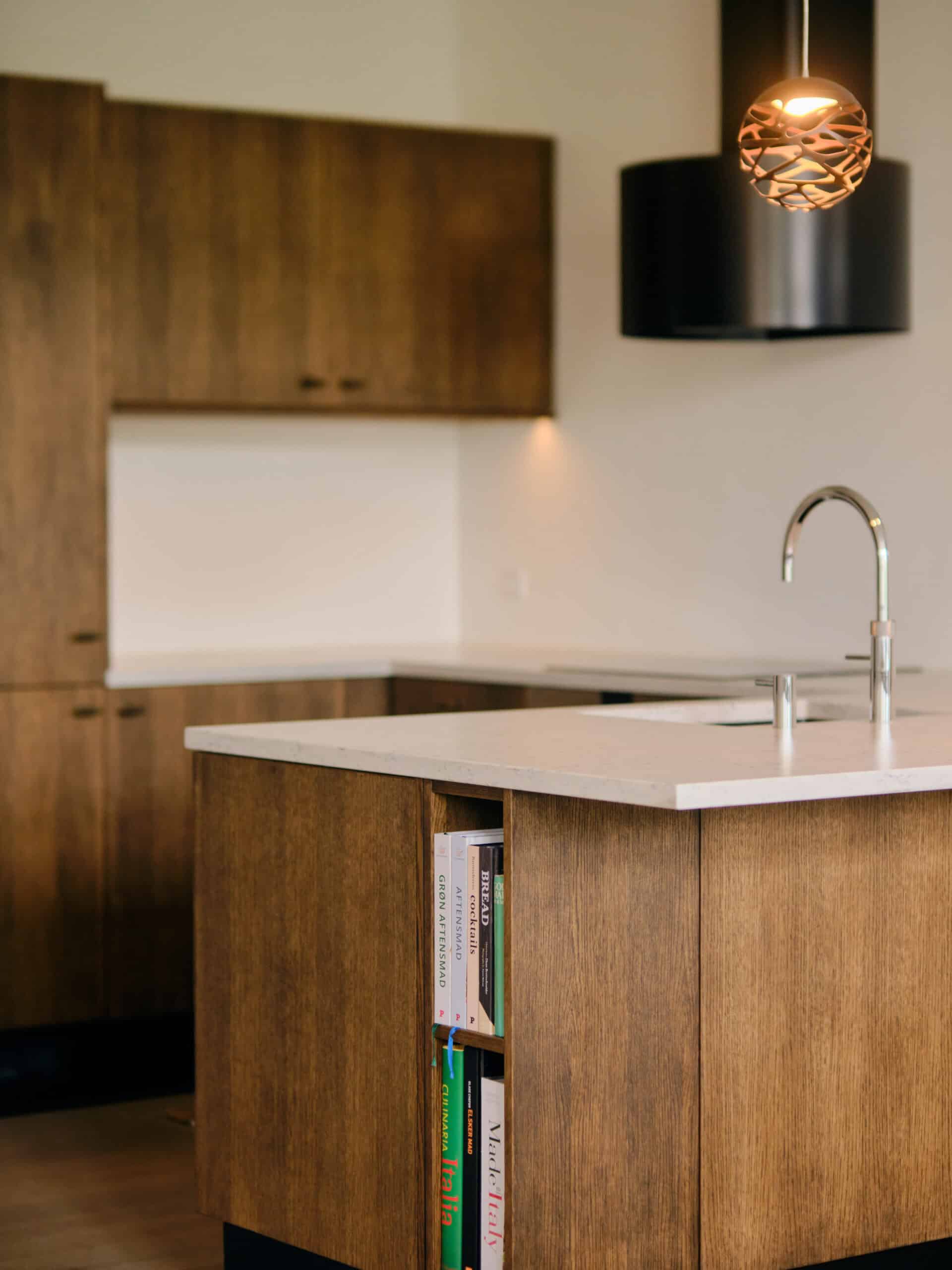 Billede af moderne køkken med træskabe og hvide bordplader.