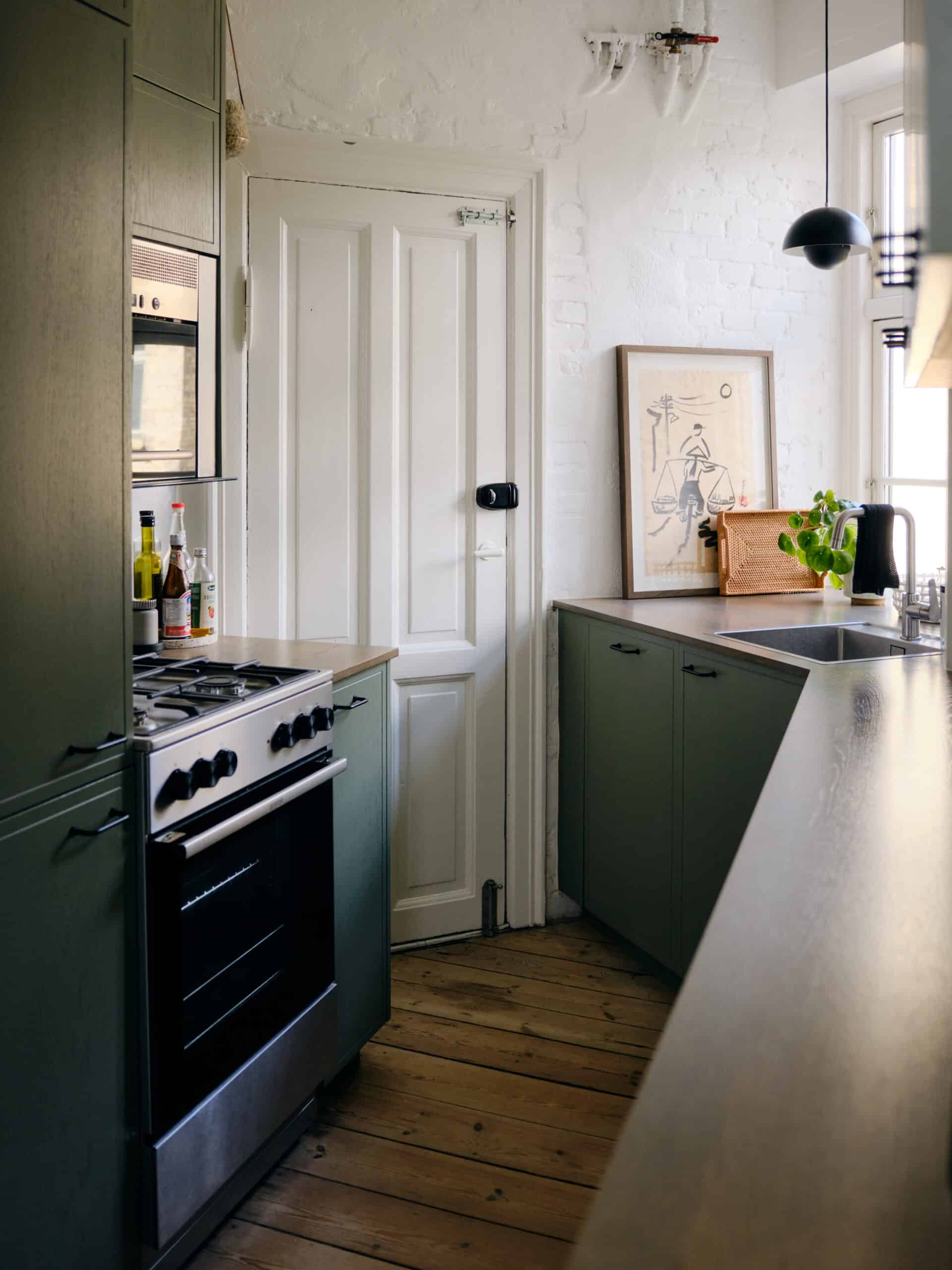 Børnevenlig køkken med grønne skabe og rustikt trægulv. Modernisering og funktionelt design af Signatur Snedkeri.