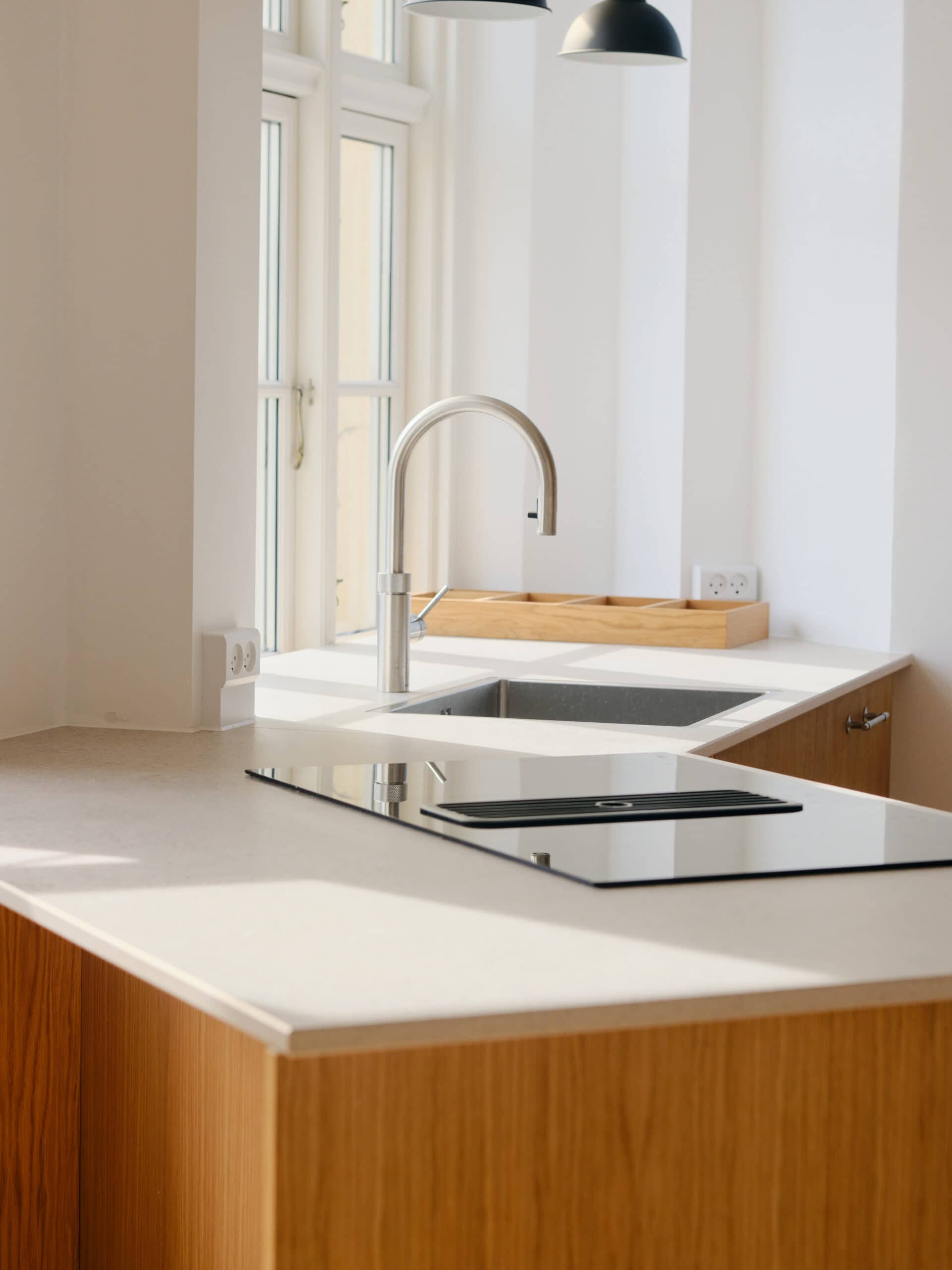 Moderne køkken med træ- og hvidt bord og stor vask overfor vindue.