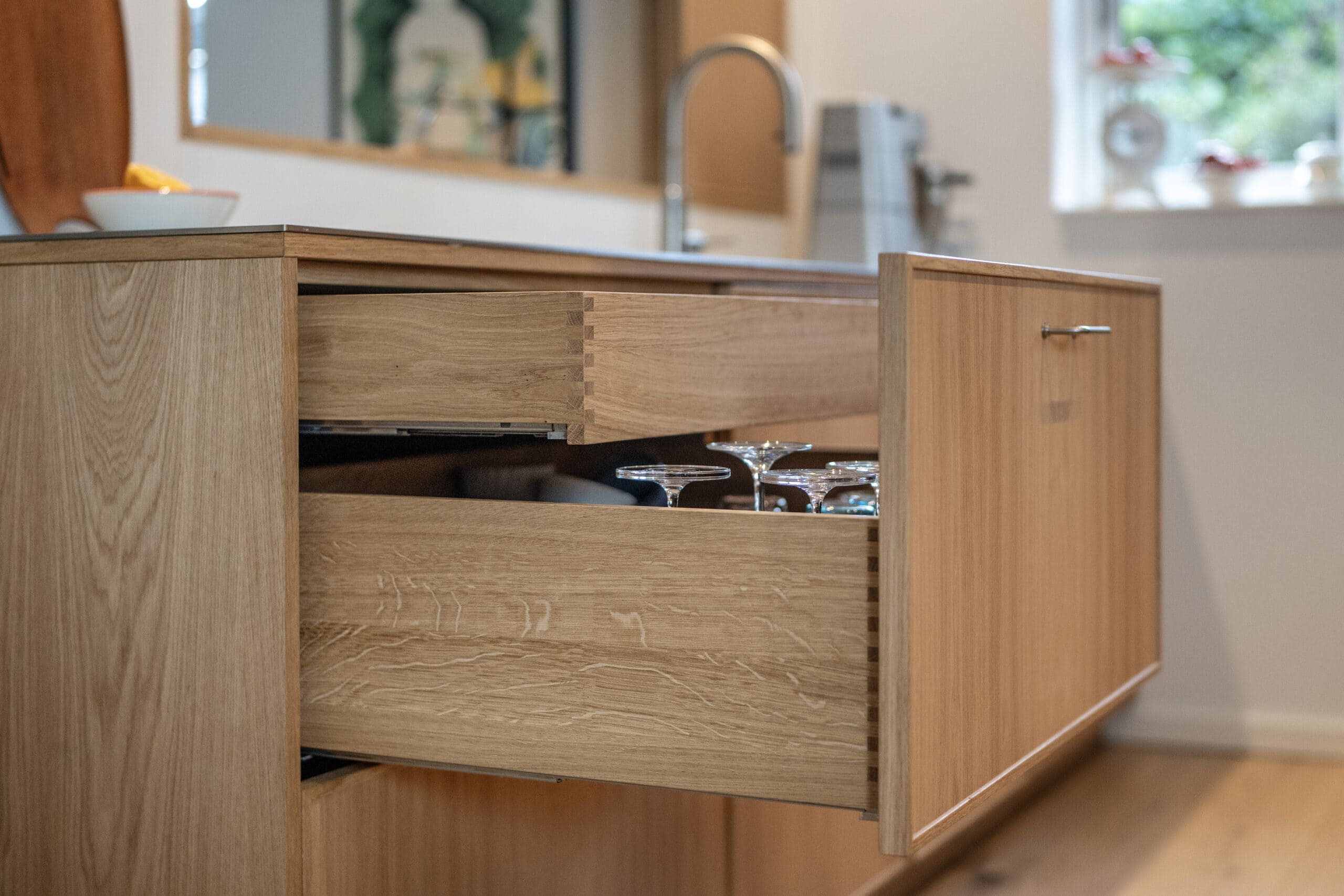 Elegant træskab med udtræk til glas i moderne køkken, specialfremstillet i høj kvalitet.