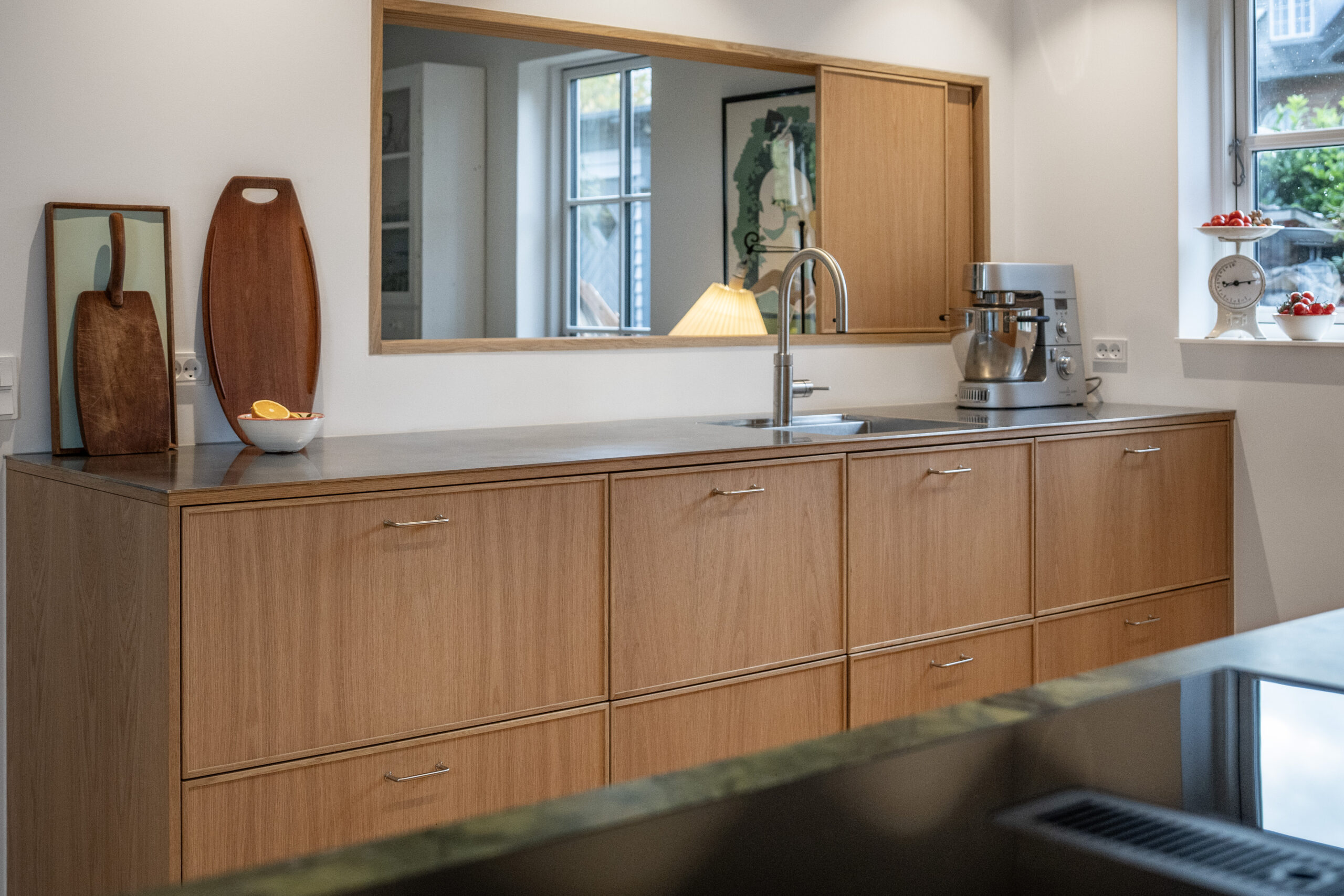 Billedet viser et moderne køkken med træskabe og stålarmatur.