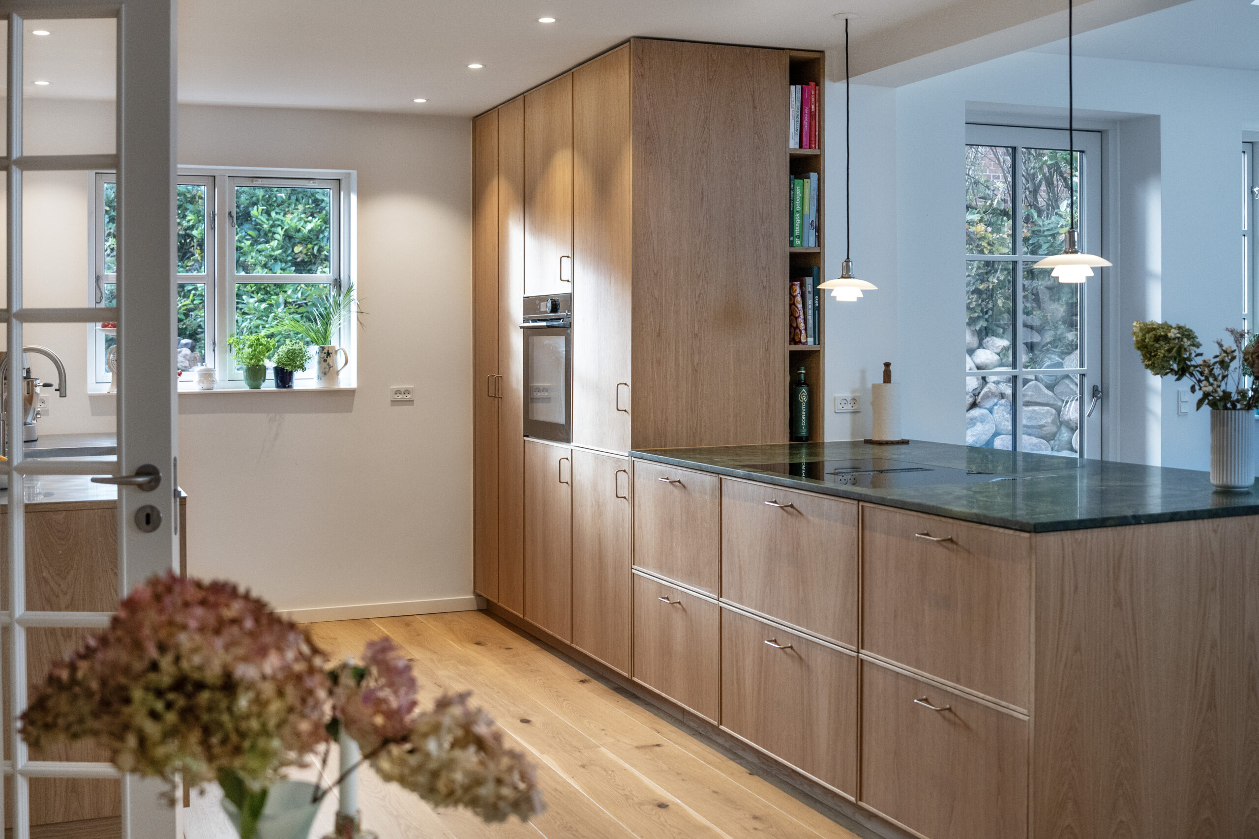 Akustisk køkken med rustikke trælåger og grøn granitbord.