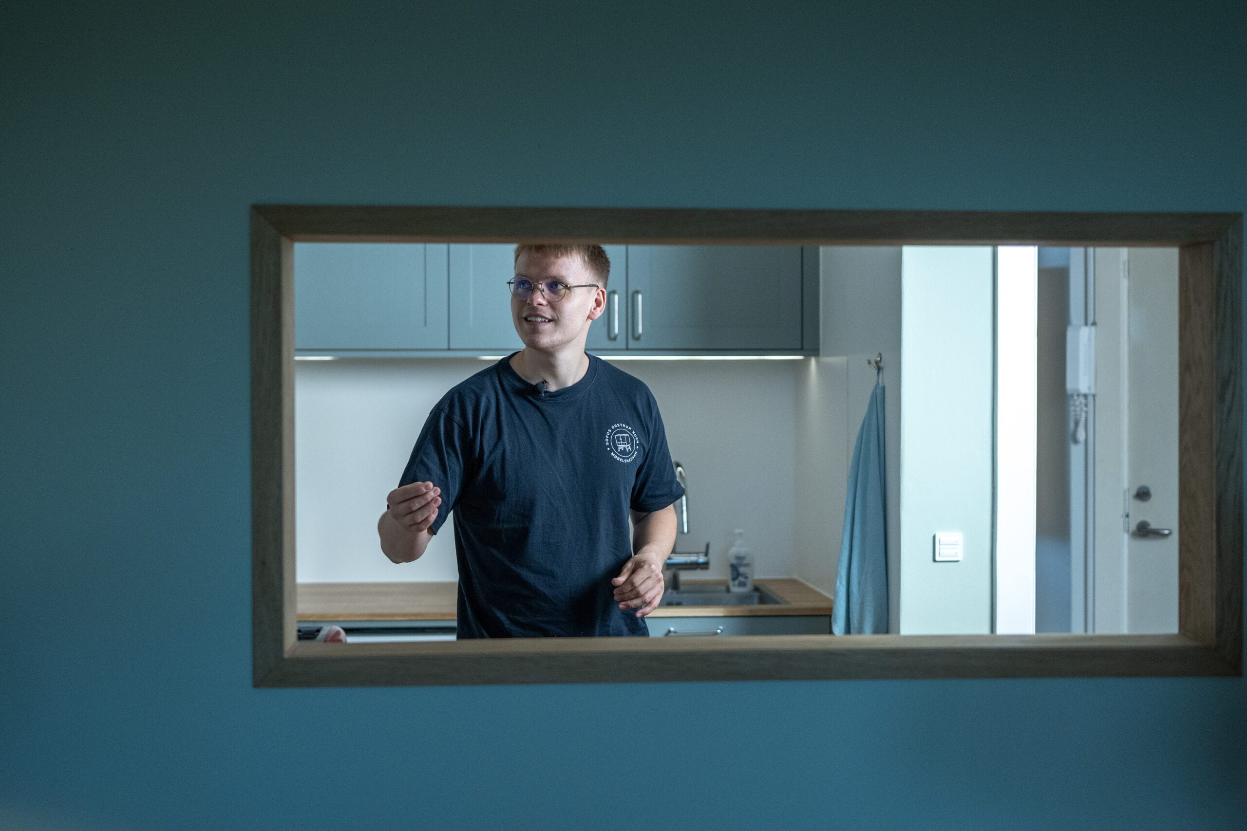 Modellør i moderne køkken set gennem vægåbning.