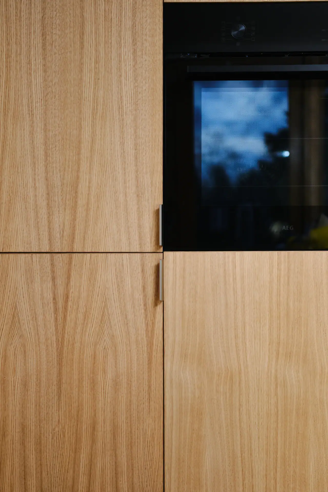 Høvlet trækabinet med indbygget ovn i moderne køkken.