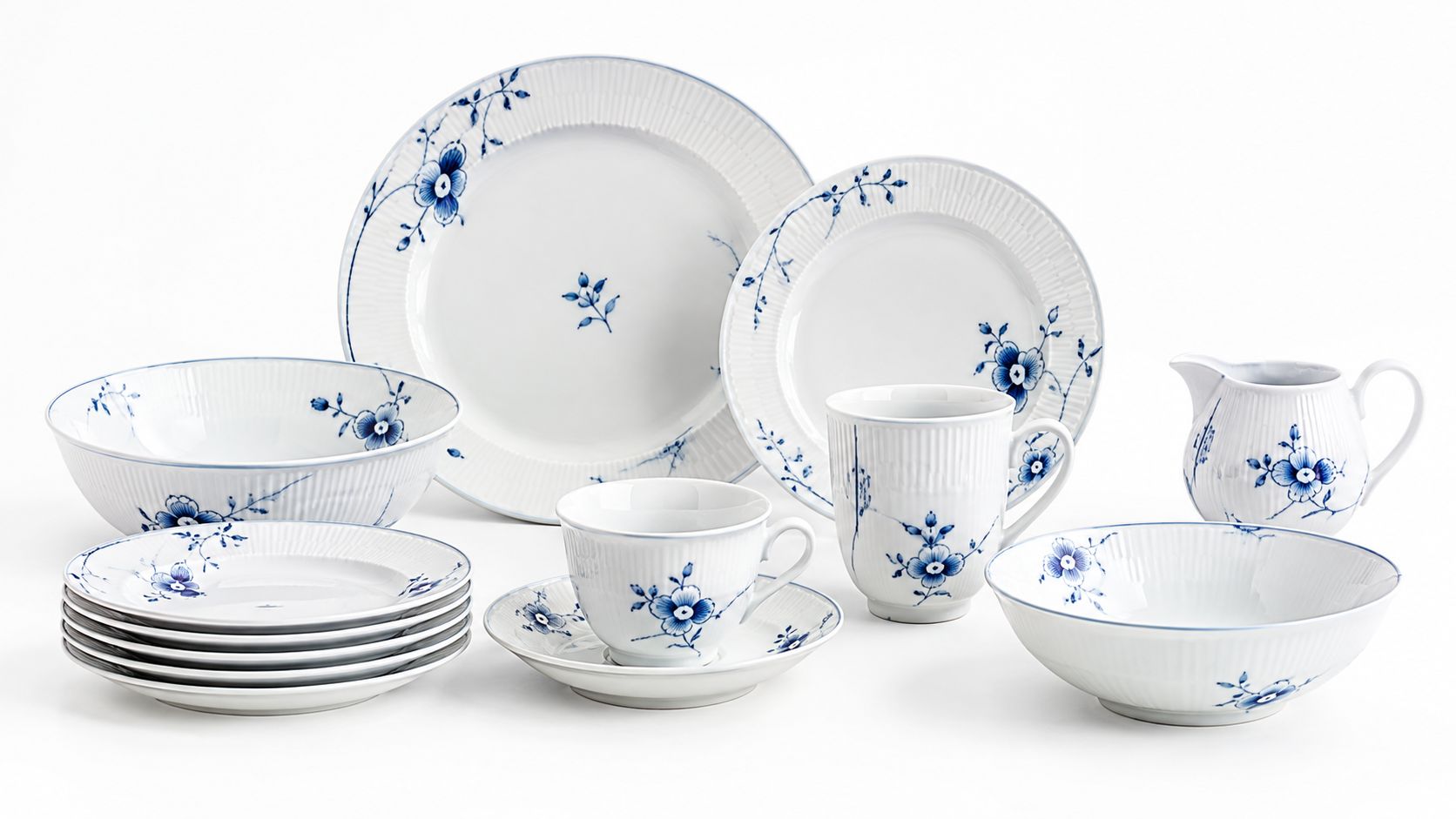 Et elegant porcelænssæt fra Royal Copenhagen med blåt blomstermønster og riflet kant på hvid baggrund.